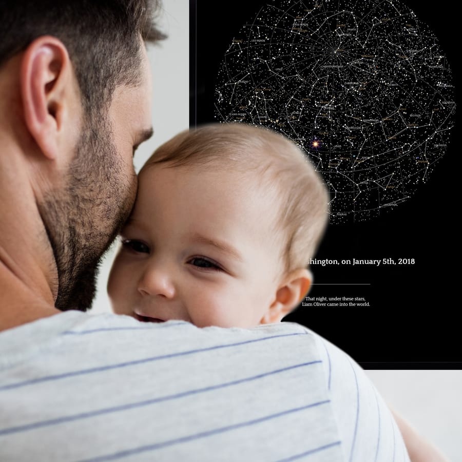 Ein junger Vater mit einem Baby vor der Sternenkarte zur Erinnerung an die Geburt des Babys